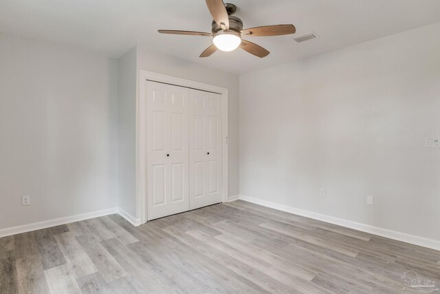 unfurnished bedroom with ceiling fan, light hardwood / wood-style flooring, and a closet