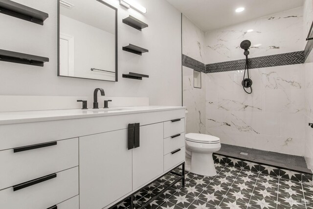 bathroom featuring toilet, a tile shower, and vanity