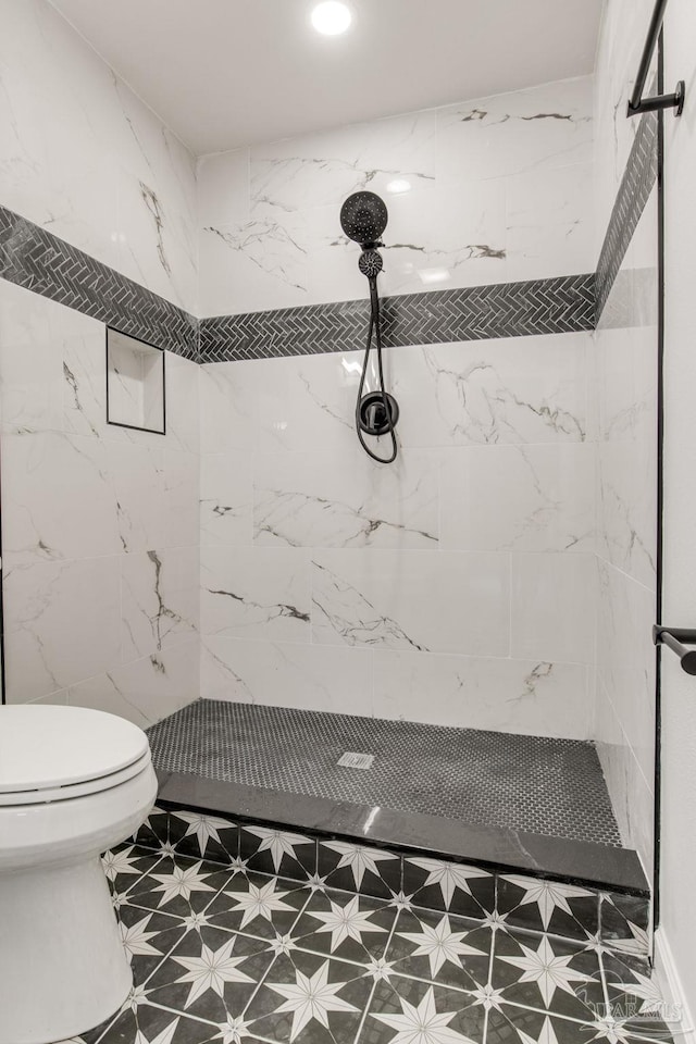 bathroom with a tile shower and toilet