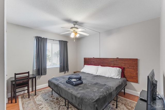 bedroom featuring ceiling fan, light wood-style flooring, and baseboards