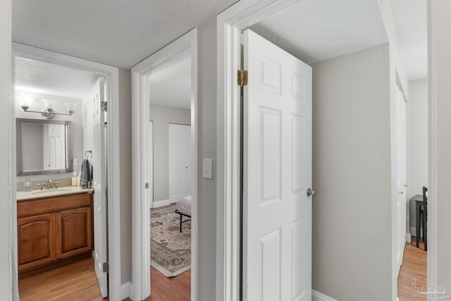 bathroom with baseboards, a textured ceiling, vanity, and wood finished floors