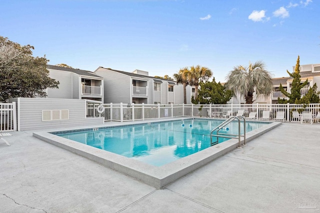 community pool with a patio area and fence