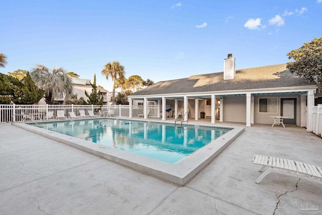 community pool with a patio area and fence