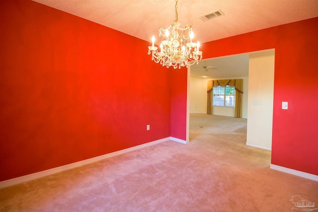 carpeted empty room featuring a chandelier, baseboards, and a ceiling fan
