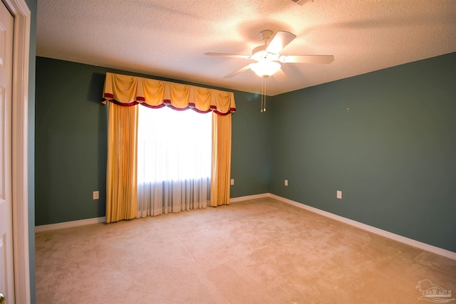 empty room featuring ceiling fan, light carpet, a textured ceiling, and baseboards
