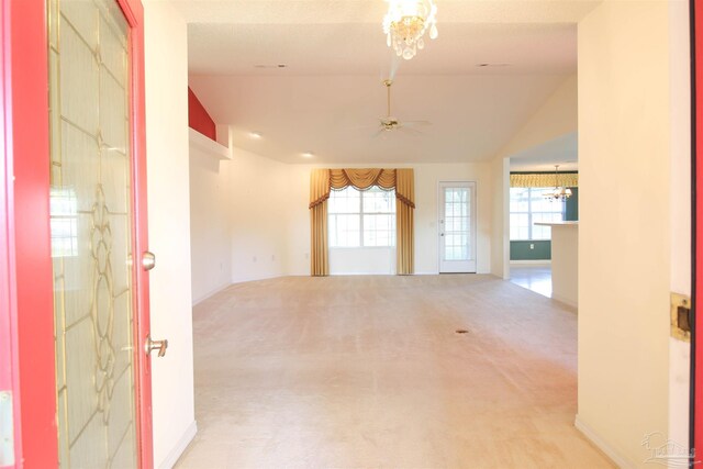 unfurnished room featuring ceiling fan, vaulted ceiling, a chandelier, and carpet floors