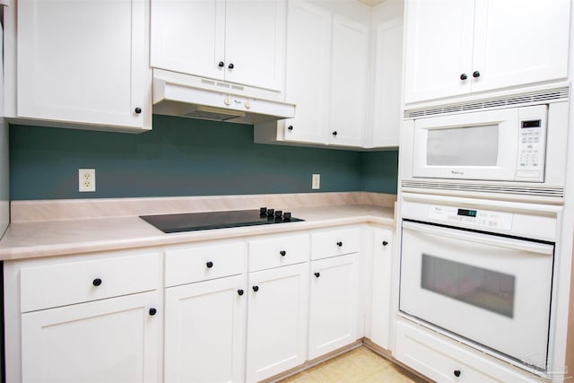 kitchen with white appliances, under cabinet range hood, light countertops, and white cabinets