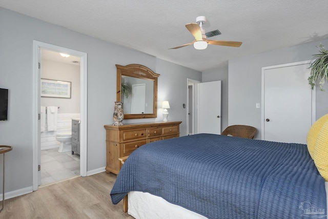 bedroom with light hardwood / wood-style floors, a textured ceiling, connected bathroom, and ceiling fan