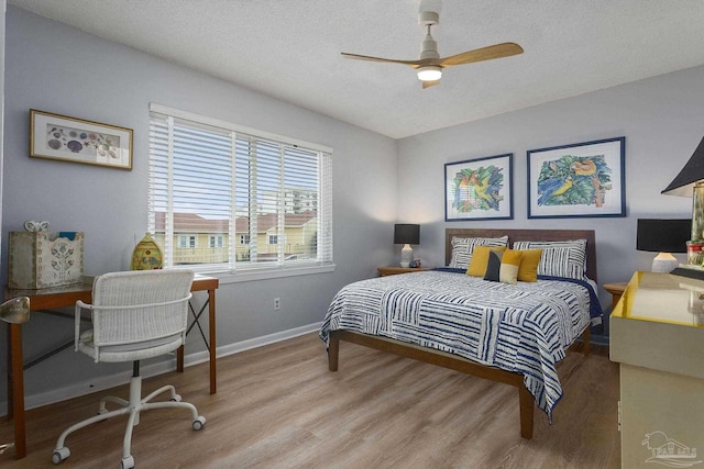 bedroom featuring ceiling fan, hardwood / wood-style floors, and a textured ceiling