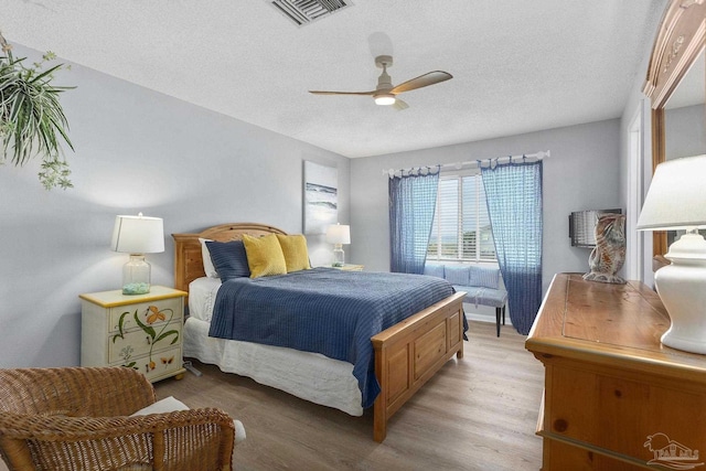 bedroom featuring light wood-type flooring, ceiling fan, and a textured ceiling