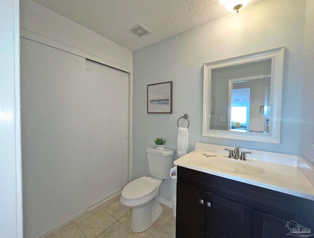 bathroom with tile patterned flooring, a textured ceiling, vanity, and toilet