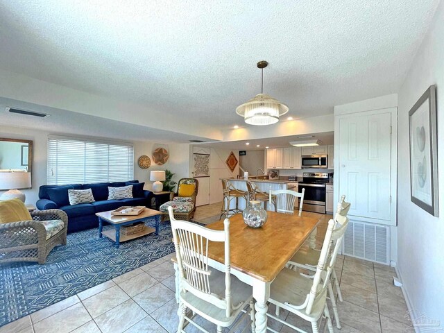 dining room with a textured ceiling, sink, and light tile patterned floors