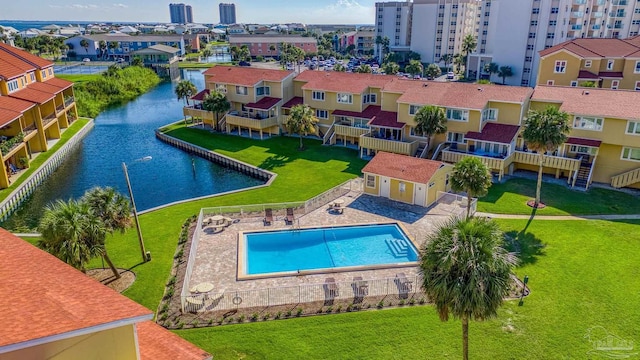 view of swimming pool featuring a lawn, a water view, and a patio area