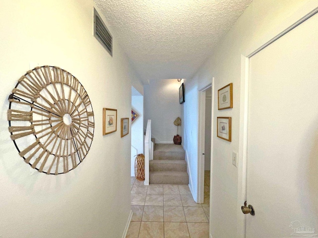 hall featuring a textured ceiling and light tile patterned floors