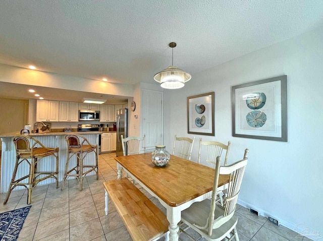 dining area with a textured ceiling and light tile patterned floors