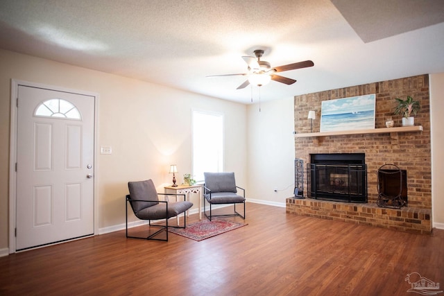 living area featuring a textured ceiling, a fireplace, and wood finished floors