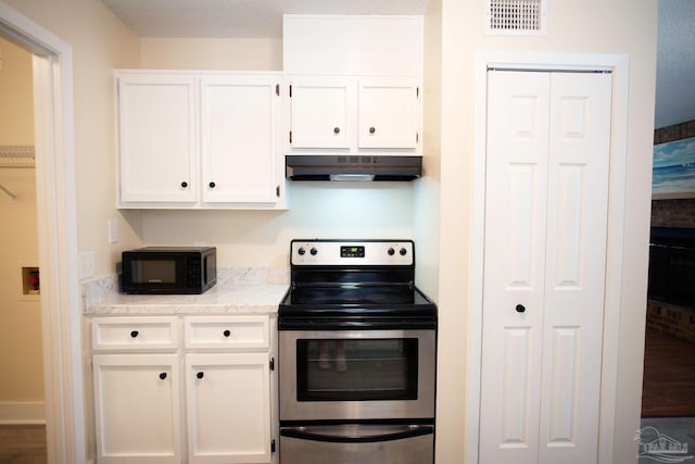 kitchen featuring visible vents, stainless steel range with electric cooktop, white cabinetry, black microwave, and under cabinet range hood