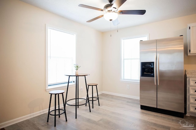 dining area with a ceiling fan, light wood-type flooring, and baseboards