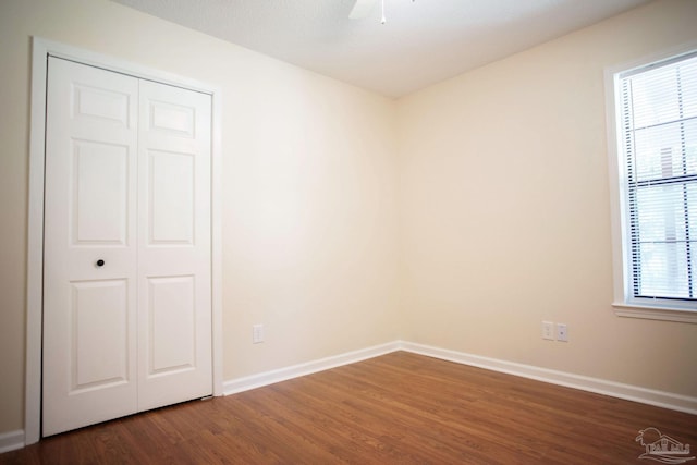 unfurnished bedroom with a ceiling fan, a closet, dark wood finished floors, and baseboards