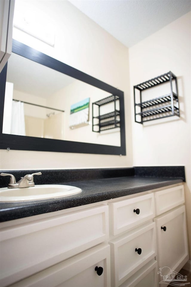 room details featuring a shower with shower curtain and vanity