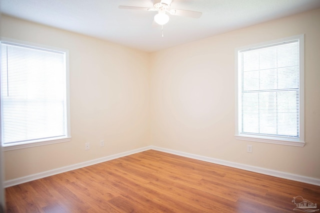 spare room featuring ceiling fan, light wood-style floors, and baseboards