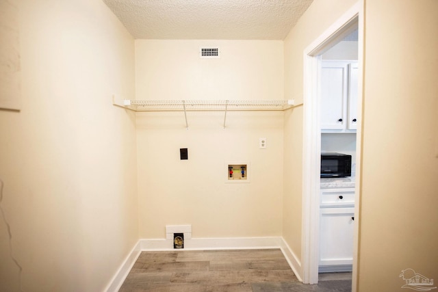 laundry room featuring laundry area, visible vents, wood finished floors, a textured ceiling, and washer hookup