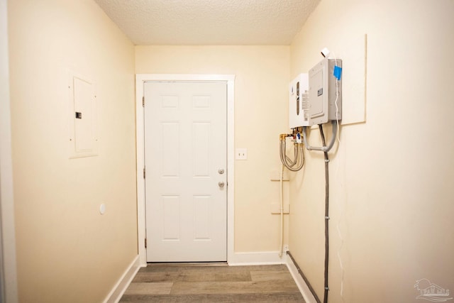 interior space featuring a textured ceiling, electric panel, baseboards, and wood finished floors