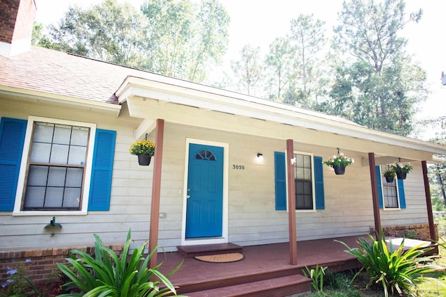 property entrance with a porch and a shingled roof