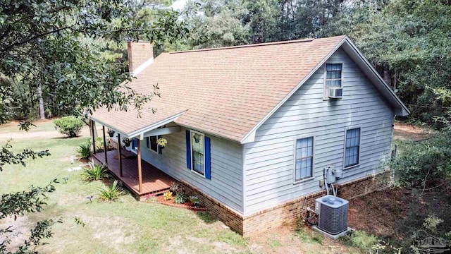 exterior space featuring cooling unit, a lawn, a chimney, and central air condition unit