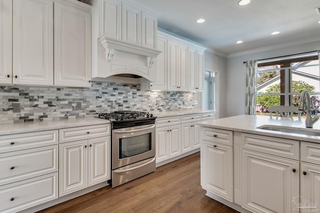 kitchen featuring stainless steel range with gas cooktop, ornamental molding, light wood-style floors, white cabinetry, and a sink