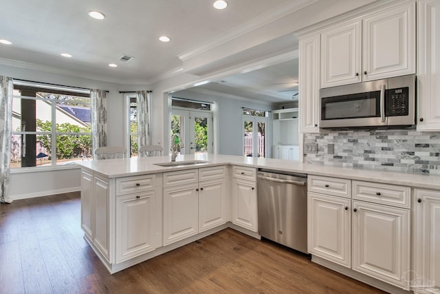 kitchen featuring tasteful backsplash, appliances with stainless steel finishes, ornamental molding, french doors, and a sink