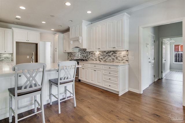 kitchen featuring light countertops, ornamental molding, gas stove, and dark wood finished floors