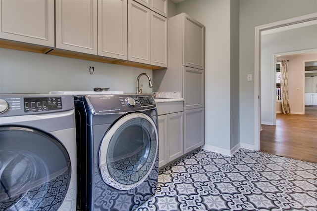 laundry room with a sink, washing machine and clothes dryer, cabinet space, and baseboards