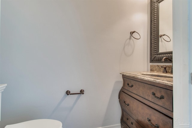 half bath featuring vanity, toilet, and baseboards