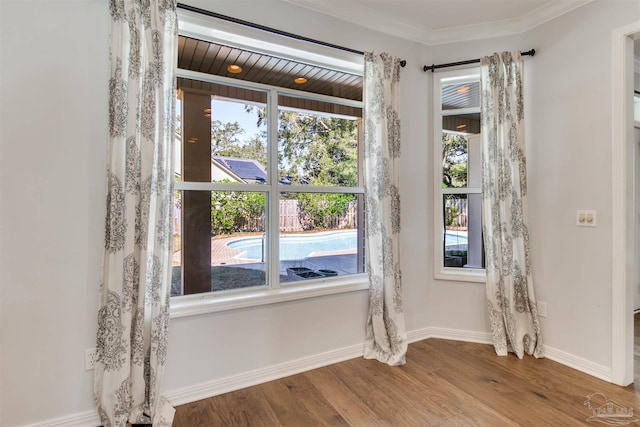 unfurnished dining area featuring baseboards, wood finished floors, and ornamental molding