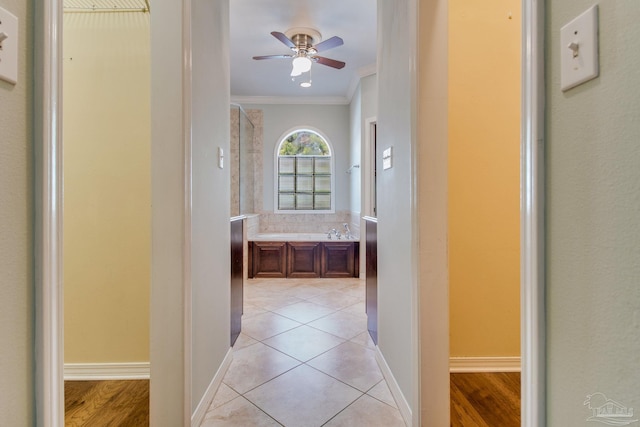 corridor with light tile patterned floors, ornamental molding, and baseboards