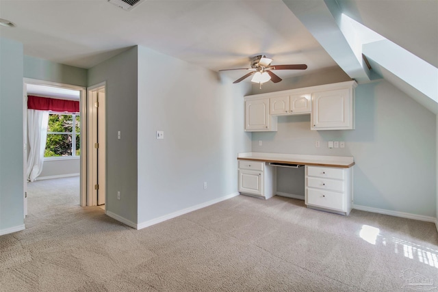 kitchen with light carpet, built in desk, baseboards, and white cabinets