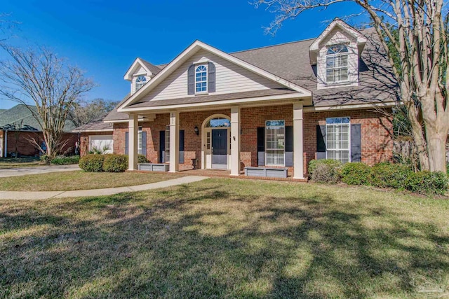 view of front of home with a front yard, covered porch, and brick siding