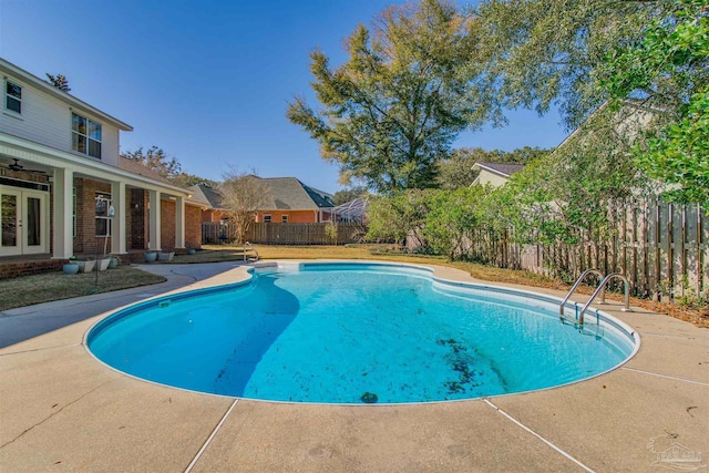 view of swimming pool featuring a patio area, fence, a fenced in pool, and french doors