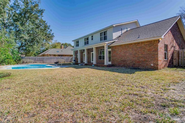 back of house with a fenced in pool, brick siding, a shingled roof, a lawn, and fence