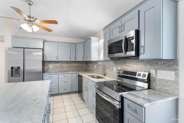 kitchen with light stone countertops, appliances with stainless steel finishes, tasteful backsplash, sink, and light tile patterned flooring