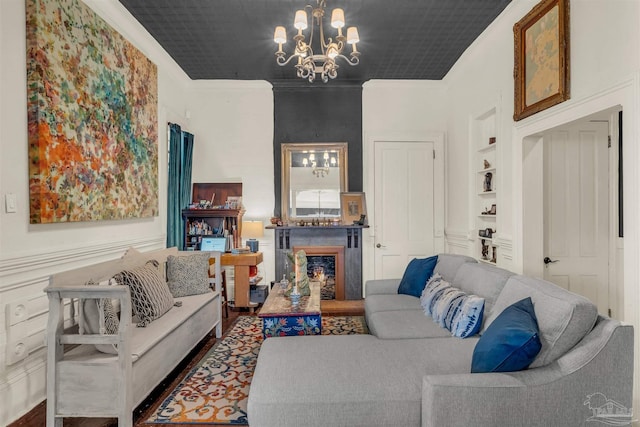 living room featuring hardwood / wood-style flooring, built in shelves, crown molding, and a chandelier