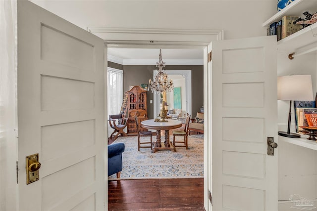 corridor featuring dark wood-type flooring, crown molding, and a notable chandelier