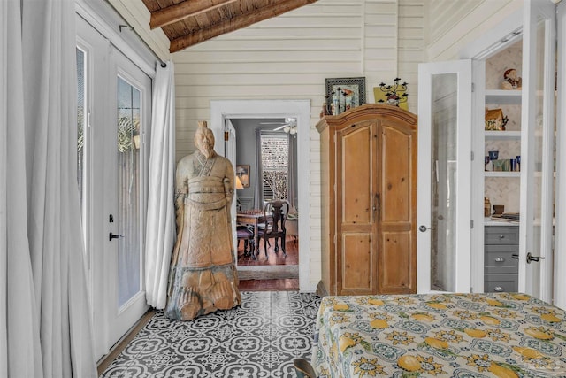 bedroom featuring tile patterned flooring, lofted ceiling with beams, wood ceiling, and wooden walls