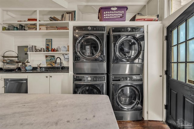 laundry room featuring dark hardwood / wood-style flooring, sink, and stacked washer and clothes dryer