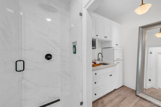 bathroom with wood-type flooring, vanity, and an enclosed shower