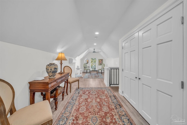 corridor with light wood-type flooring and vaulted ceiling