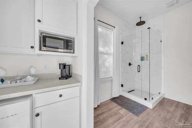 bathroom with hardwood / wood-style floors and a shower with shower door