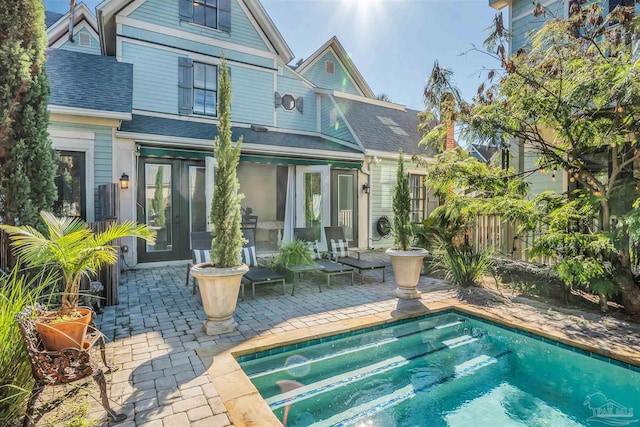 rear view of property featuring a patio area and a fenced in pool