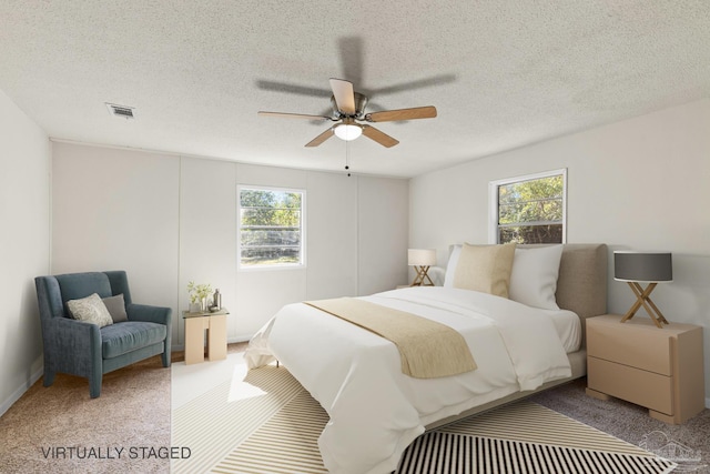 carpeted bedroom featuring multiple windows, a textured ceiling, and ceiling fan